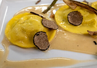 Italian food, fresh home made red potato stuffed pasta tortellacci or ravioli dumplings with summer black truffle and cripsy green asparagus, Parma, Emilia Romagna, Italy