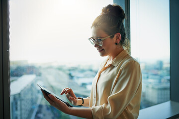 I have to admit that tablets makes work more effective. Shot of a young businesswoman browsing on a...