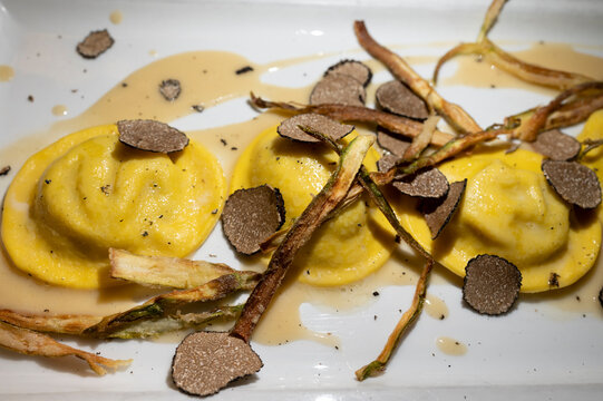 Italian food, fresh home made red potato stuffed pasta tortellacci or ravioli dumplings with summer black truffle and cripsy green asparagus, Parma, Emilia Romagna, Italy