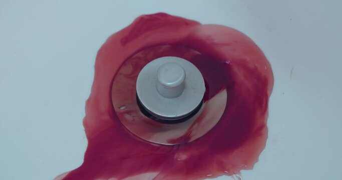 Close-up of blood washing down a shower drain.