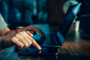 Fingers touch mobile phone concept, Businessman hand using laptop and smart phone working at home office.