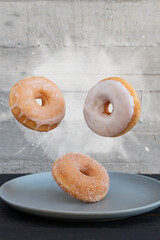 Flying donuts. Mix of multicolored donuts on powder splashes on gray background