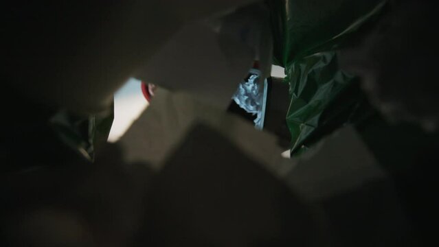The man dumps a basket full of garbage. Bottom view from the trash bin. Irresponsible separation and recycling
