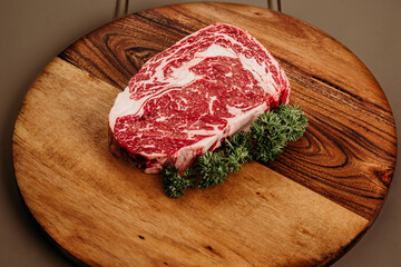 Raw red meat with parsley on a cutting wooden board 