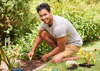 Gardening is so relaxing and rewarding. Portrait of a handsome young man working in his garden.