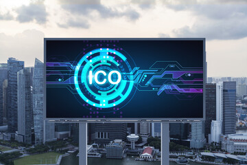 ICO hologram icon on billboard over panorama city view of Singapore at sunset. The hub of blockchain projects in Southeast Asia. The concept of initial coin offering, decentralized finance