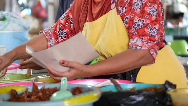Indonesian old woman is preparing "Nasi Jagung" for customers. Nasi jagung is a Traditional food from Indonesia