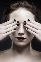 See no evil. A beautiful pale woman with dark lipstick covering her eyes.