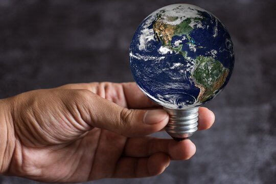 world light bulb in hand, Man holding blue earth, Save earth concepts. Elements of this image furnished by NASA