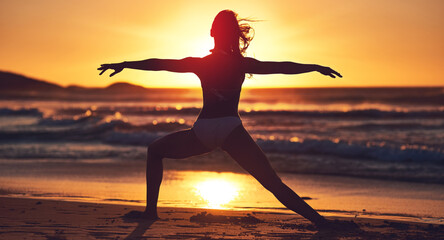Be at peace not in pieces. Silhouette of young woman practising yoga on the beach.