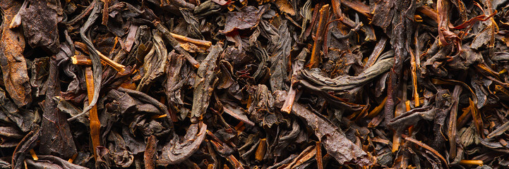 Black large-leaf tea as abstract background. Texture of dry black tea leaves. Dark background. Macro black tea leaf