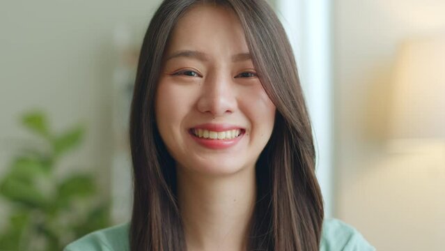 Close up portrait of young Asian woman look at camera and smile at home.