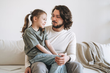 Young happy family with father and daughter on sofa in the cozy home, father day