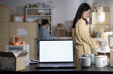 Laptop with blank white screen standing on the desktop. Asian women online seller checking stock...
