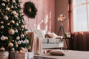 New Year's interior. Gray sofa on a pink wall with a Christmas tree