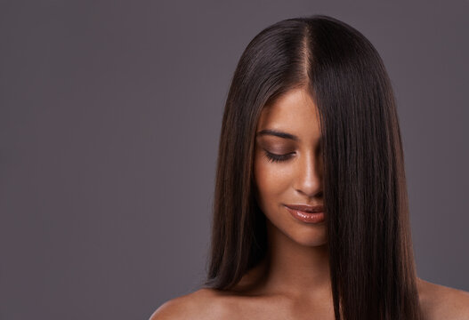 Its her crowning glory. A young woman with sleek hair posing in studio.