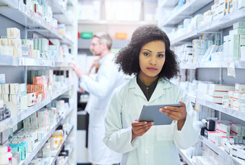 Its the smartest way to manage a modern pharmacy. Shot of a young woman using a digital tablet to...