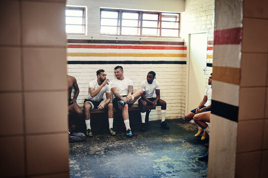 Winner sit here. Full length shot of a group of handsome young rugby players having a chat while sitting together in a locker room.