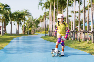 asian child or kid girl playing surf skate or skateboard in skating rink track and extreme sports...