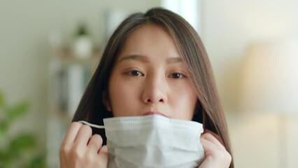 Close up of young Asian woman takes off protective mask and look at camera after coronavirus pandemic end with smile