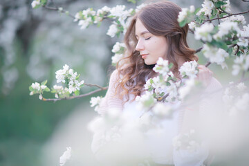 springtime fashion portrait of a young girl in a blooming cherry garden, tenderness of the morning