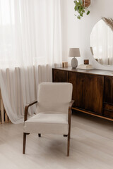 Armchair in the interior in the photo of a mirror and chest of drawers. nude interior