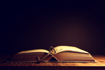 image of open antique book on wooden table with vintage key