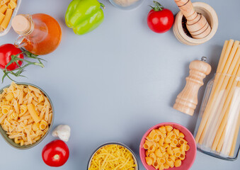 Obraz na płótnie Canvas top view of different types of macaroni as tagliatelle ziti pipe-rigate bucatini with tomato salt garlic black pepper butter on blue background with copy space
