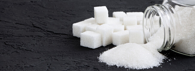 Glass jar with sugar black background banner.Diabetes. Scattered white sugar on a black table. Copy...