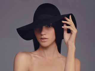 Shes got beauty and style. Studio shot of a beautiful woman wearing a hat against a gray background.