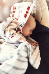 Fast asleep. High angle shot of a tired little infant child sleeping on his mothers chest while being covered in blankets at home during the day.