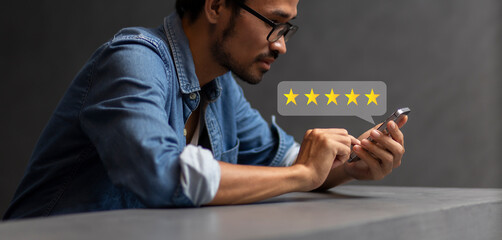Man using mobile phone and pressing five stars icon during sitting  at home, satisfaction service review concept