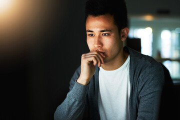 Working through the night. Shot of a handsome young male programmer working late in his office.