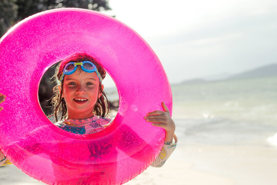 Girl on the beach with a pink floater