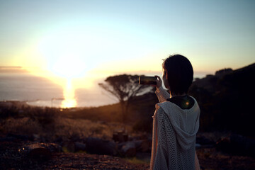 Fototapeta premium I just have to capture this view. Shot of a woman taking pictures on her cellphone of the sunset.