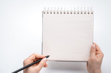 woman hands lefty writing in empty notebook at white desk. person holding pen over blank notebook on white background