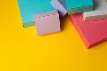 Colorful cardboard boxes on yellow background, copy space