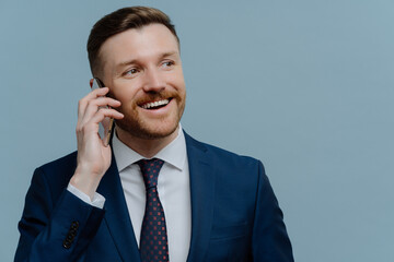 Happy successful businessman in suit making business call, talking with partner and smiling