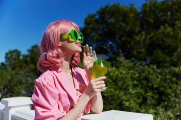 portrait of beautiful woman in pink dress outdoors with cocktail Happy female relaxing