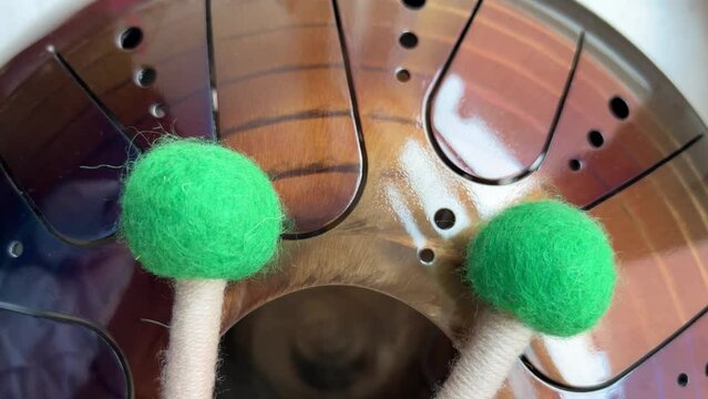 A musical instrument, a glucophone, a drum with a metal tongue on a wooden background. A modern musical instrument with wooden sticks. A tool for meditation, relaxation, with a deep magical sound