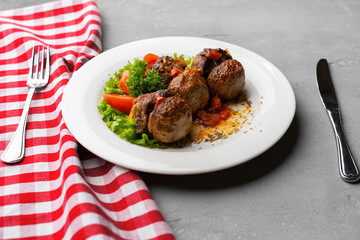Cooked meat with fresh vegetable salad on a white plate