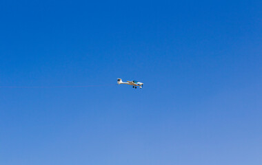 Fototapeta na wymiar Ultra light, cessna plane from side with prolonge rope on blue sky. Sport, transportation background