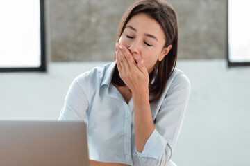 Close up portrait of tired caucasian woman office worker yawns covers mouth sitting at the...