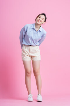 Full length image of young Asian woman posing on pink background