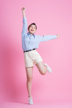 Full length image of young Asian woman posing on pink background