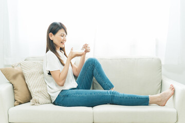ソファでヨーグルトを食べる女性（笑顔）

