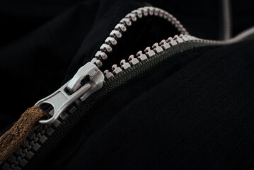 Lock with a gray zipper on black clothes close-up. Jacket clasp