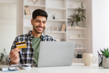 Smiling young man using pc and credit card, selective focus