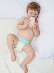 Relaxing with my formula. Full length shot of a sweet little baby lying down drinking a bottle of...