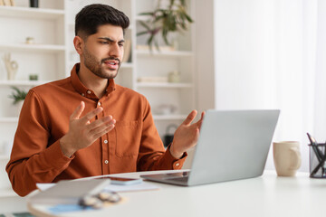 Confused Arab guy using laptop looking at screen